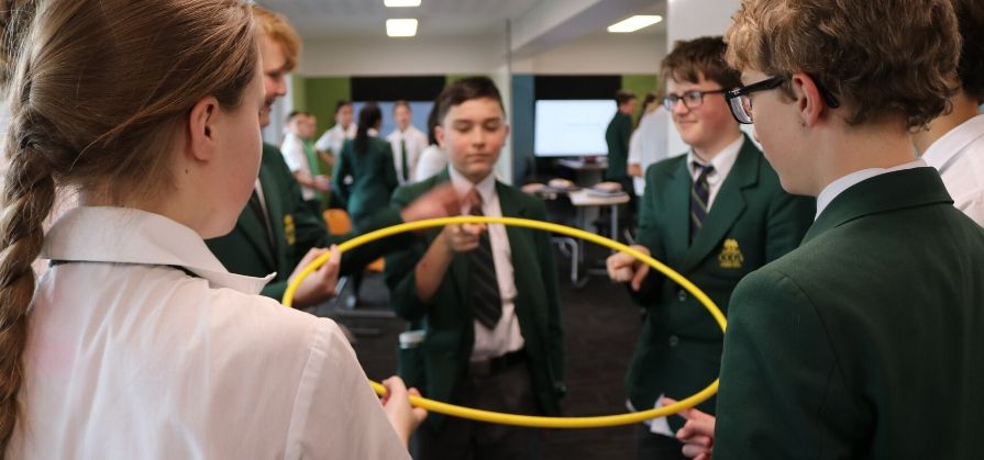 Students attempt to balance a hula hoop as a team